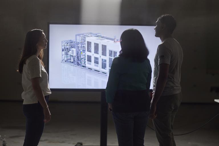 Three engineers looking at 3D rendering of PEM electrolyzer