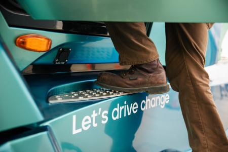 Truck driver stepping into an Accelera truck. The words "Let's drive change" are pictured on the truck step.